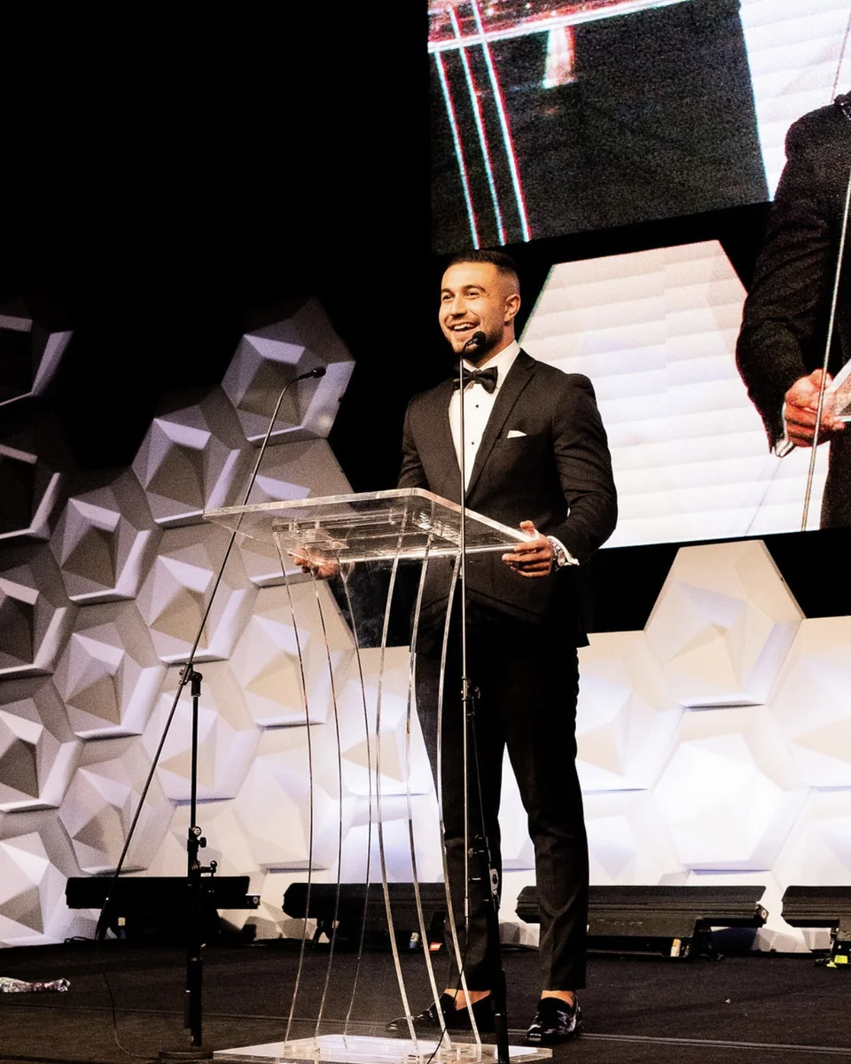 Eren Caliskan speaking on stage at a podium
